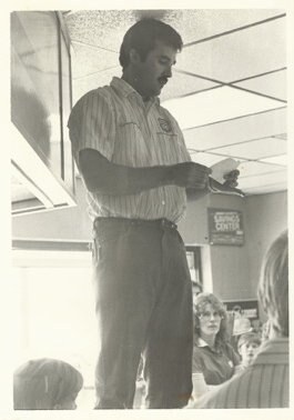 Vintage photograph of Tom Gann standing and speaking inside a store